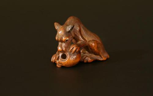 A wooden netsuke: a wolf with a skull